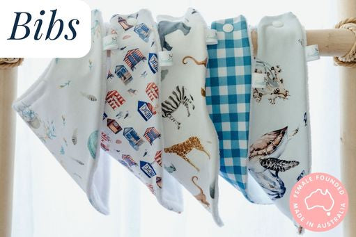 Baby bandana style bibs hanging on a bamboo frame