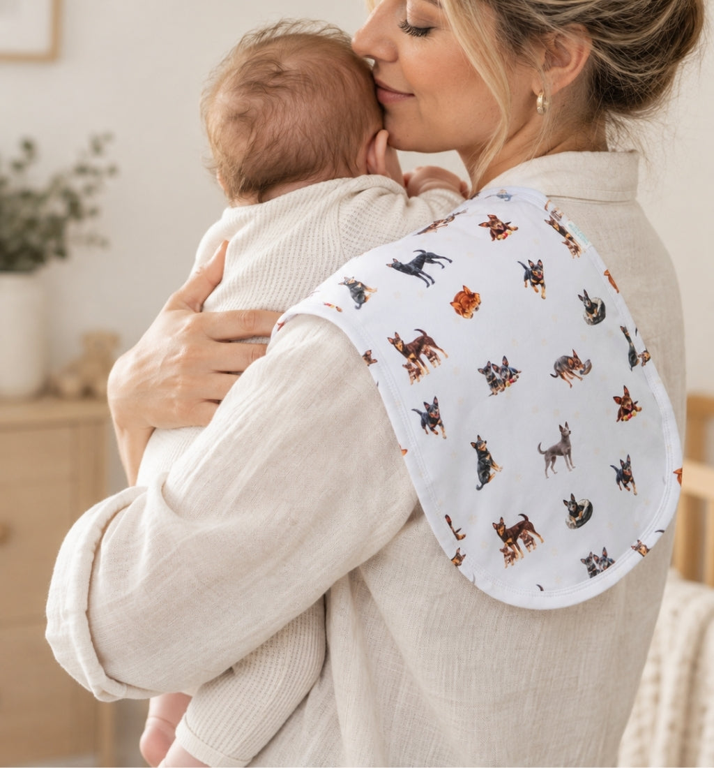 Mum cuddling her newborn over her shoulder with a dog print burp cloth