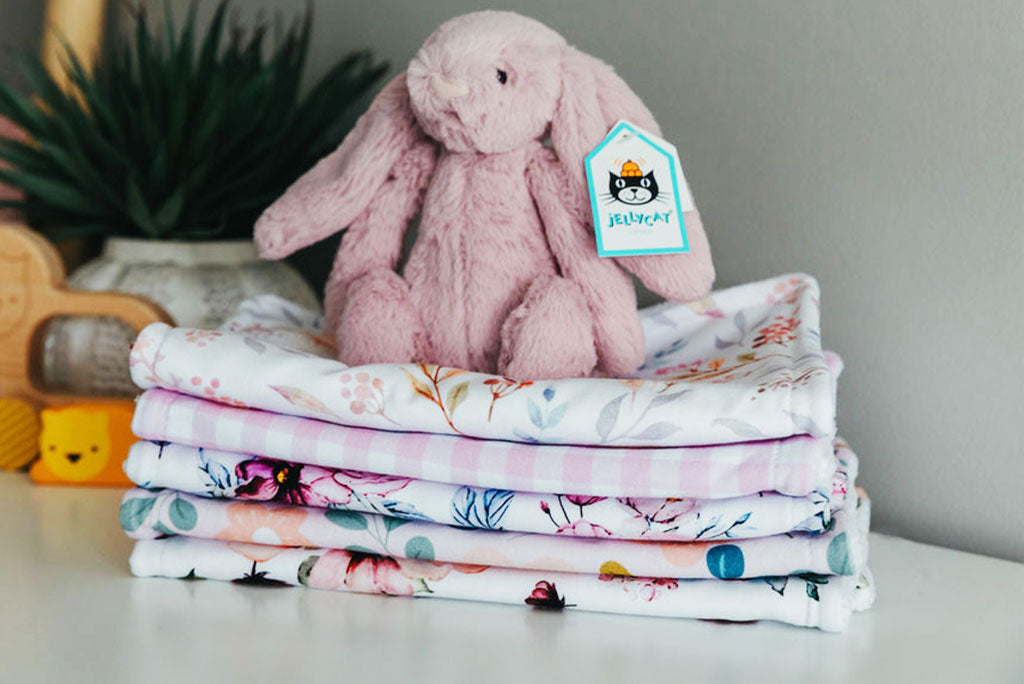 Jellycat bunny sitting on folded burp cloths