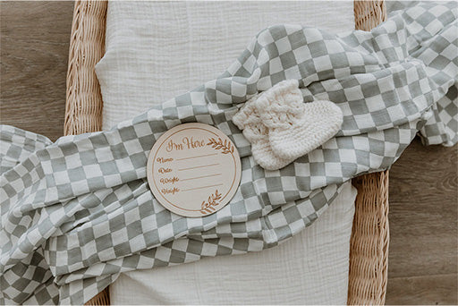 Bamboo Cotton Muslin Wrap Swaddle printed with grey and white check draped over a basket